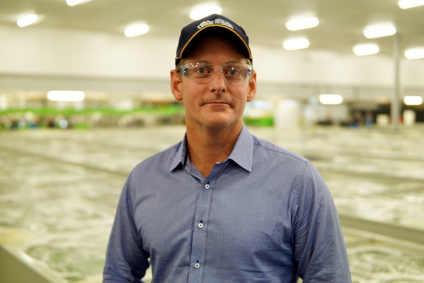 Matt stands in a warehouse, wearing plastic protective glasses.