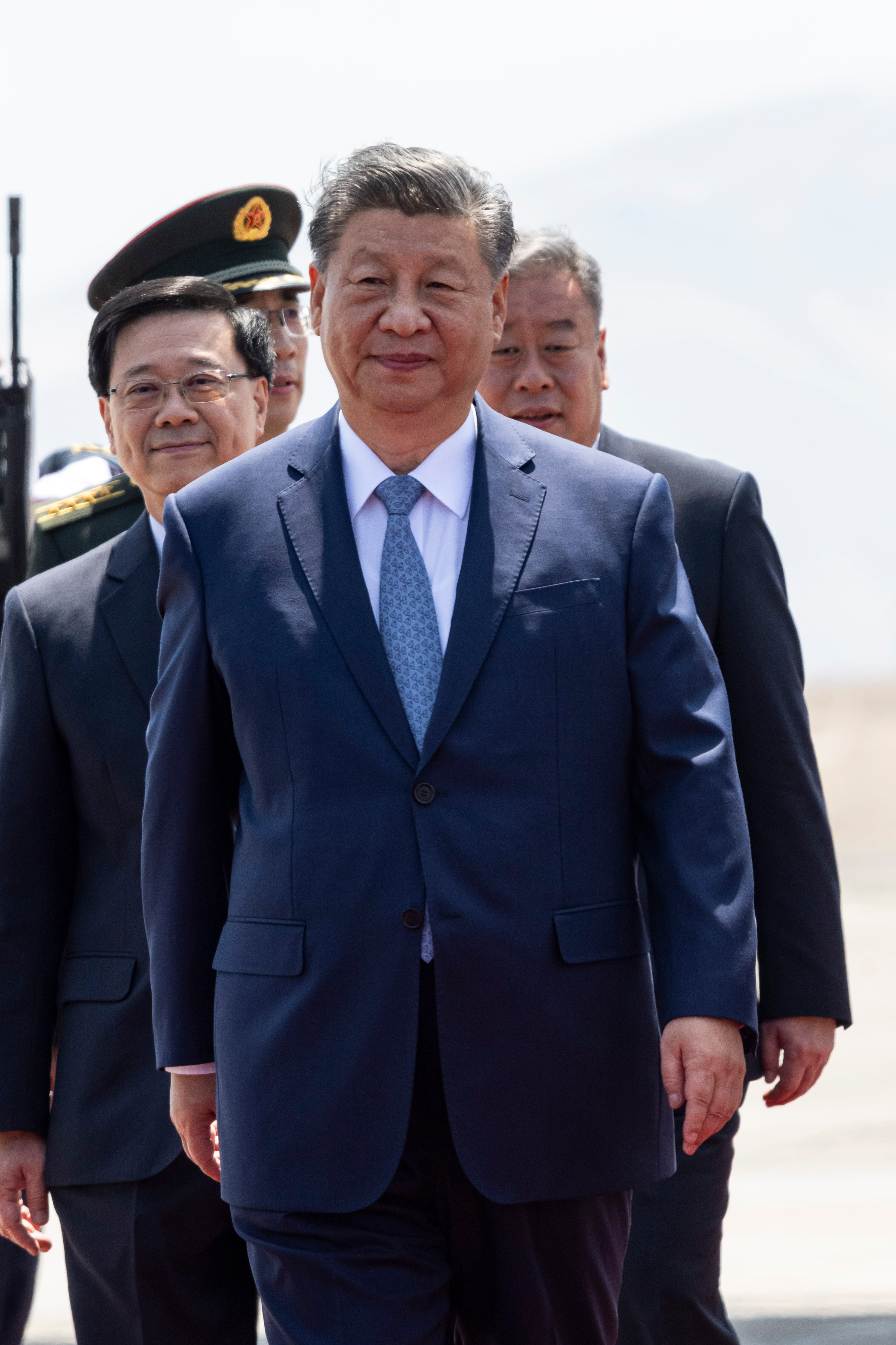 Chinese president Xi Jinping walks on a tarmac. 