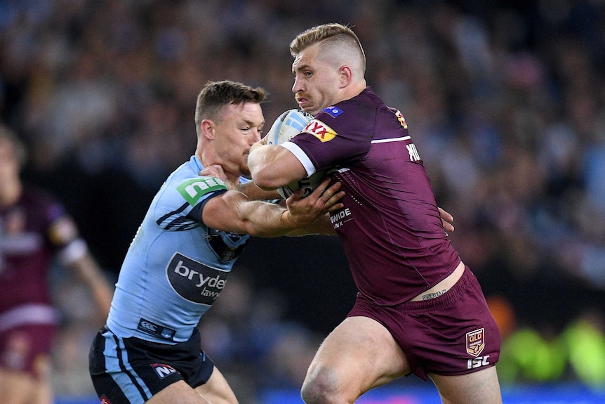 Cameron Munster fends off Damien Cook of NSW.