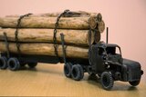 A miniature truck made of recycled materials carting miniature logs