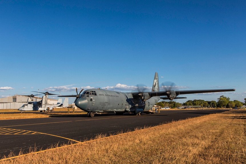 A large military cargo plane and another aircraft rest on the black tarmac at Darwin RAAF base.