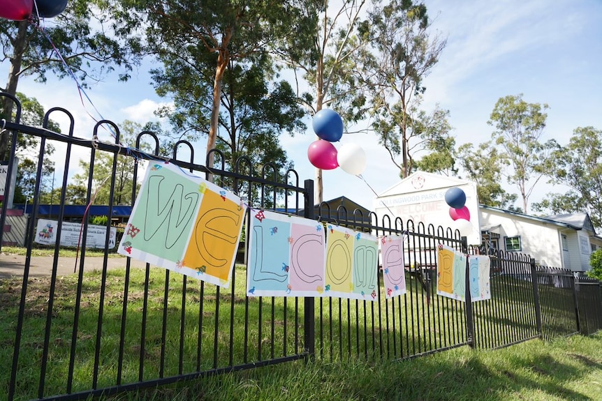 Sign on school fence says welcome back.