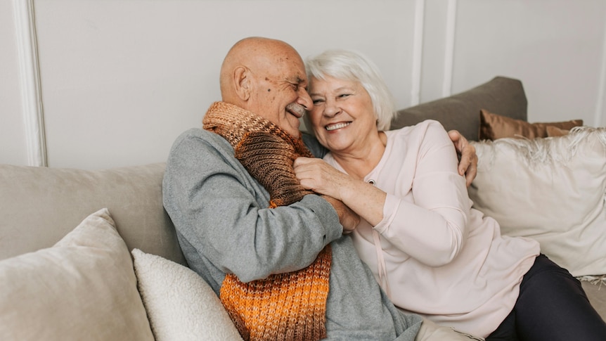 man and woman hugging and smiling on the couch