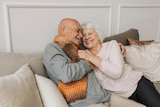 man and woman hugging and smiling on the couch