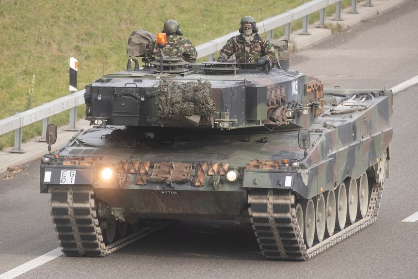 Two soldiers ride in a battle tank. 