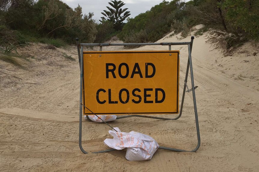 A road closed sign over the track leading to the beach where the attack happened.