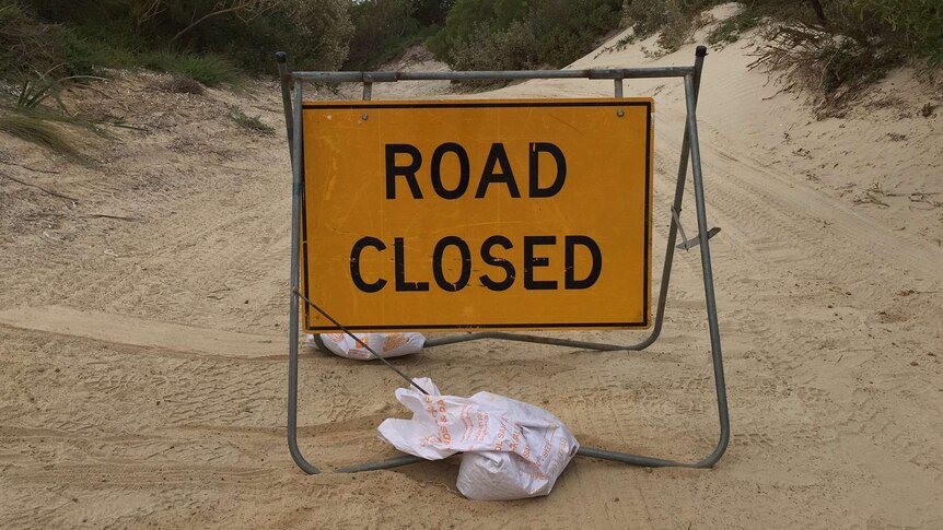 A road closed sign over the track leading to the beach where the attack happened.
