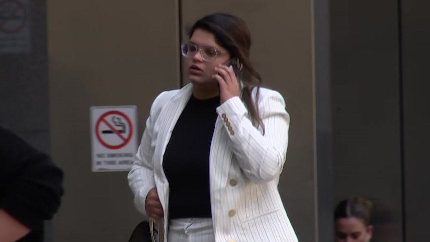 Sakshi Agrawal wearing a white suit holding a phone to her ear.