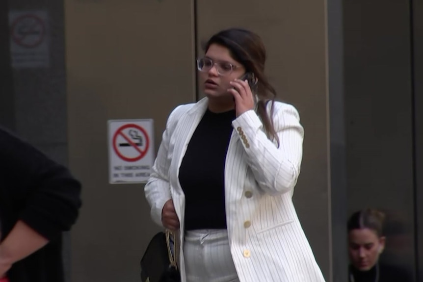 Sakshi Agrawal wearing a white suit holding a phone to her ear.