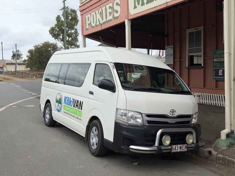 A white van is parked outside of a pub on an empty road.