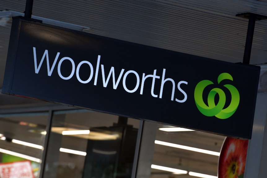 A woolworths sign, light up over the entrance to the supermarket.