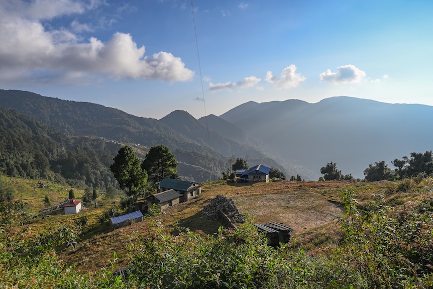 houses scattered on a hillside with mountains in the background and blue sky