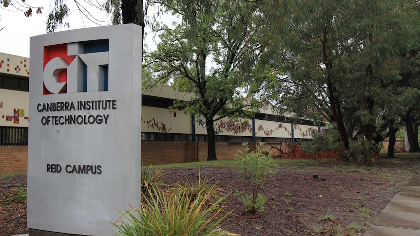 A sign reading Canberra Institute of Technology sits in front of a dark brown building.
