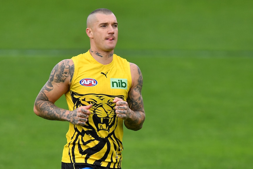 Dustin Martin purses his lips and sticks his tongue out while running at a training session