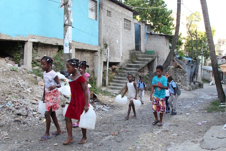 Children in a low-income neighbourhood carry containers for water