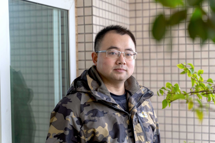 A man stands on his balcony at home.