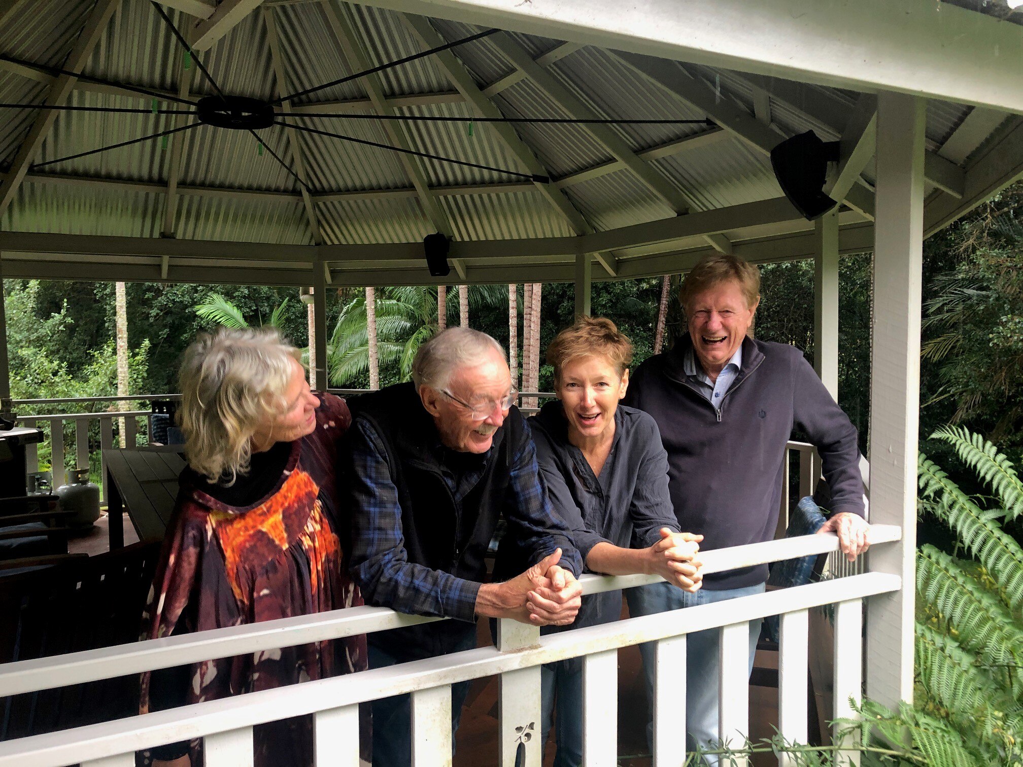 Two men and two women leaning on a railing, laughing with each other.