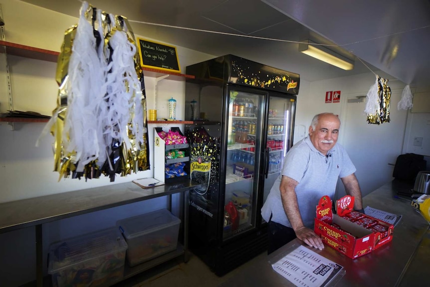 An older man stands in the canteen.