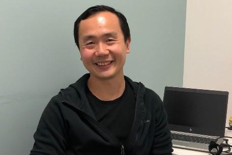 Man in black shirt and black jacket smiling at camera