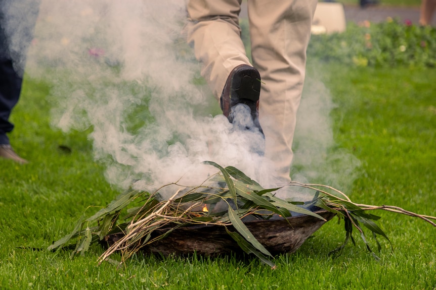 A pair of feet walking away from smoke, with one foot held up 