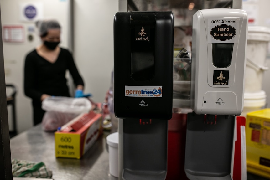 Two large automatic hand sanitiser dispensers on a wall