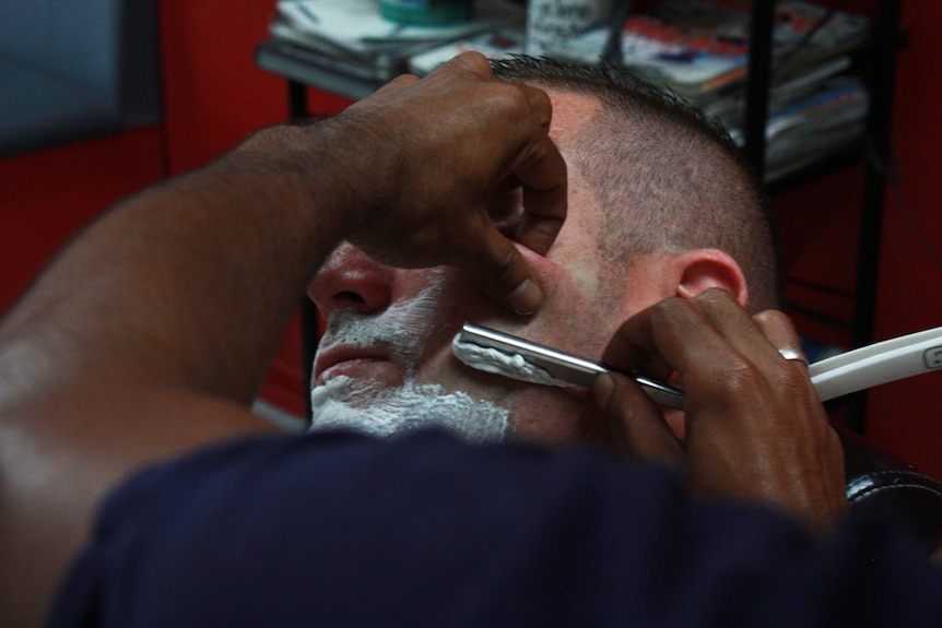 Shaving a man's face with a razor
