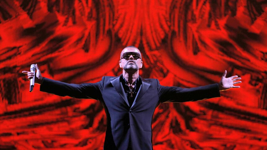 George Michael raises his arms on stage in Paris.