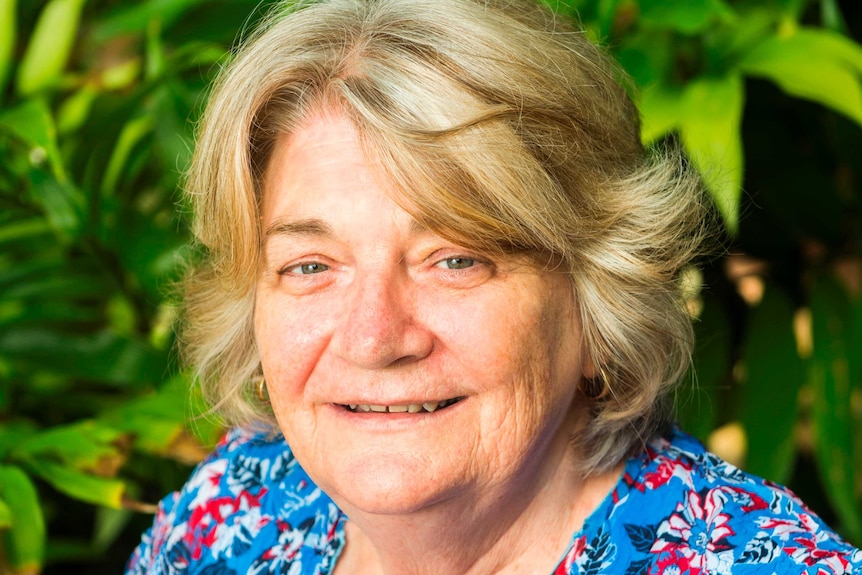 Dr Midford smiles in a professional-looking head shot, in front of a plant.