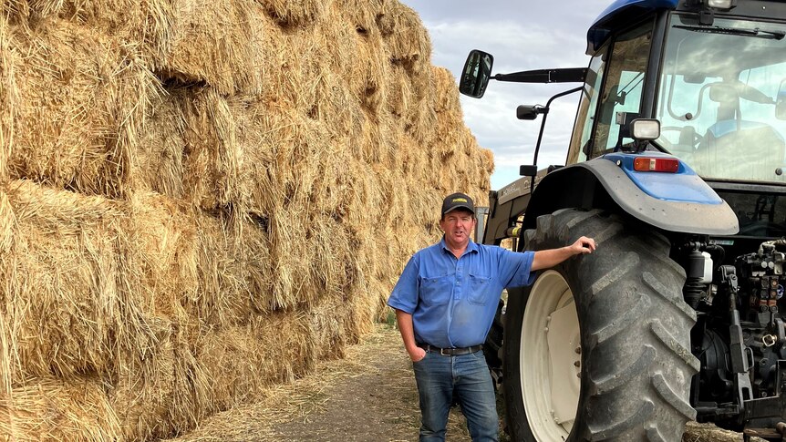 farmer Scott Tonkin standing in front of  donated fodder, destined for farmers on King Island.