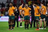 A group of glum-looking Australian rugby union players stand around on the pitch after losing a big game. 