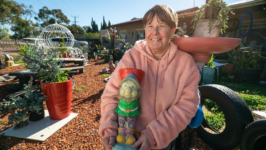 A woman wearing a pink jumper holding a gnome