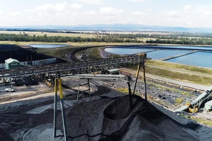 An aerial view of coal extracted from the Narrabri mine, with a landscape of lakes and mountains behind it. 