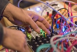 Close up of hand putting audio plug into mixing desk.