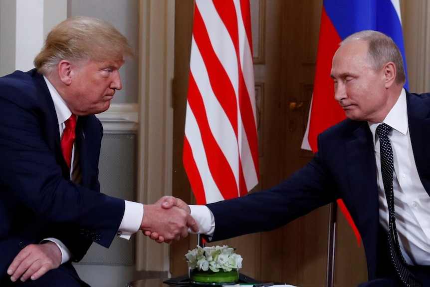 Trump and Putin shake hands in front of the Russian and US flags