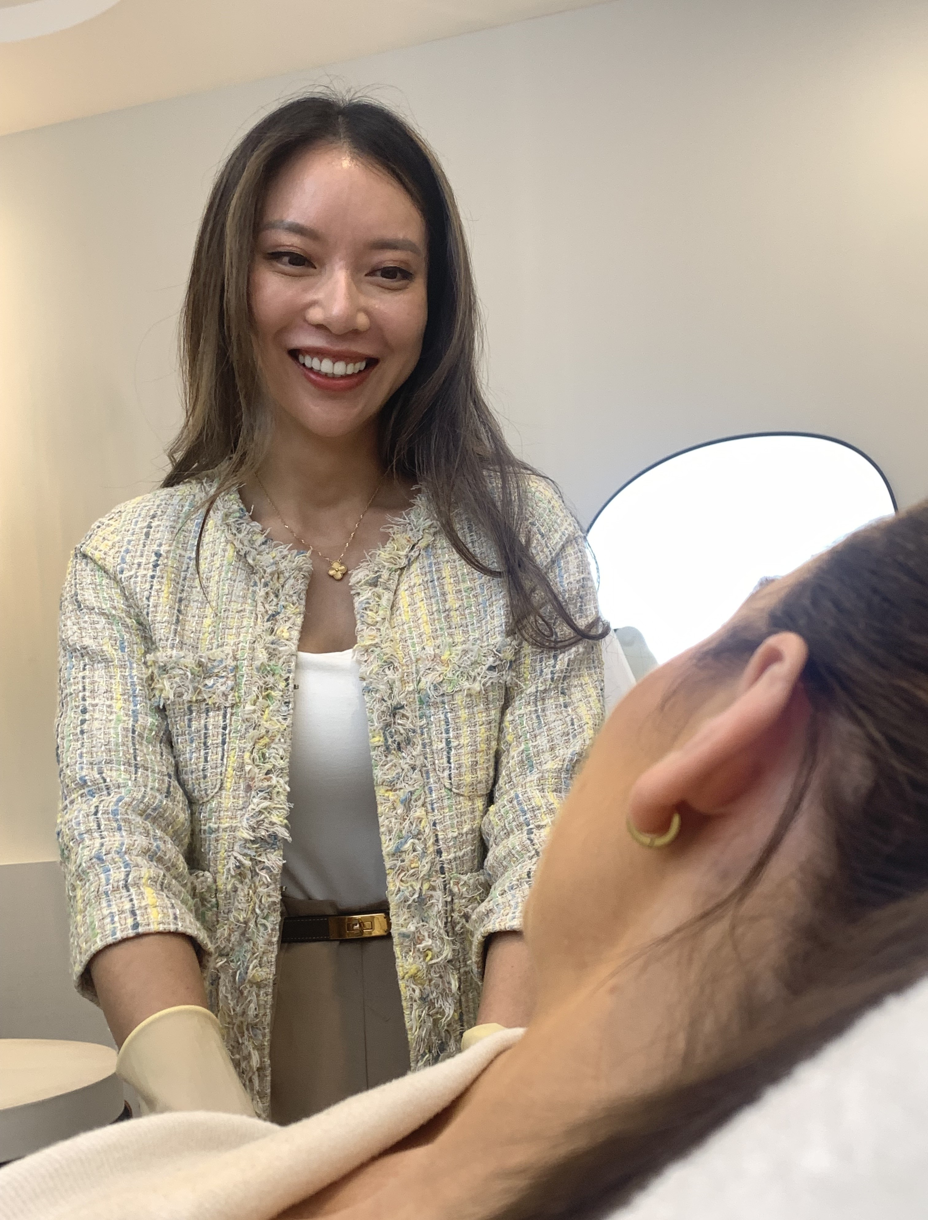 A woman smiles at another woman whose face is off camera.