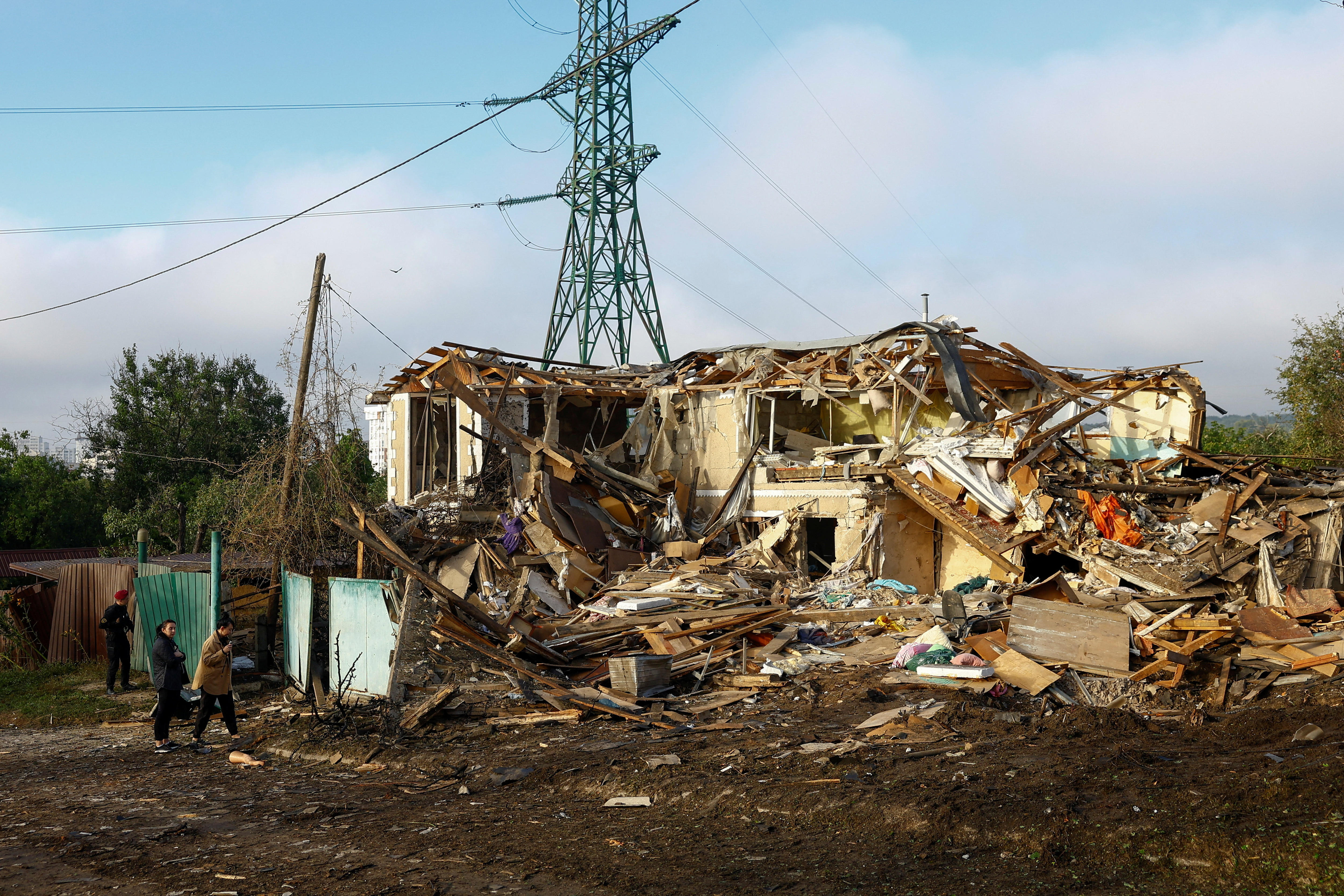 A destroyed home with power lines in the background.