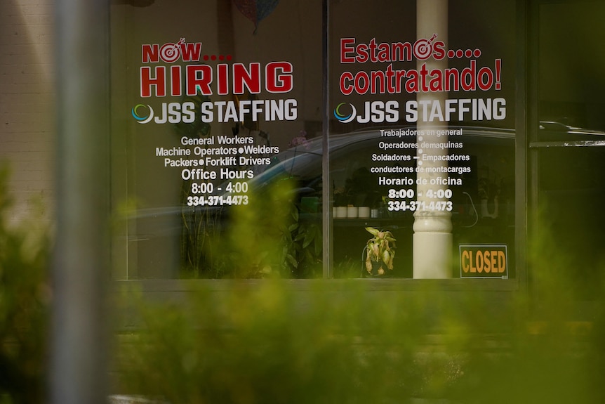 windows to an office are marked with advertisements for employment at JSS Staffing in English and Spanish