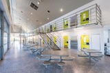 Interior view of a newly built prison with shiny new yellow doors on the cells and a metal dining table along a hallway.