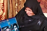 A woman cries holding a picture of her son.