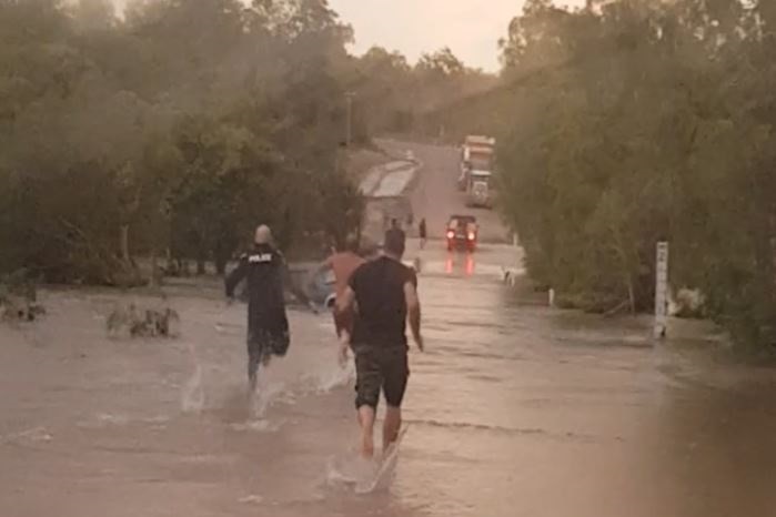 Two police officers pursue a man into floodwaters