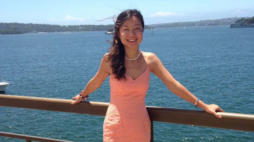 A woman smiles in front of Sydney harbour