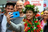Jacinda Ardern takes a selfie with fans while wearing a floral crown