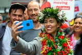 Jacinda Ardern takes a selfie with fans while wearing a floral crown