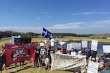 A group of protesters holding banners, flags and signs.