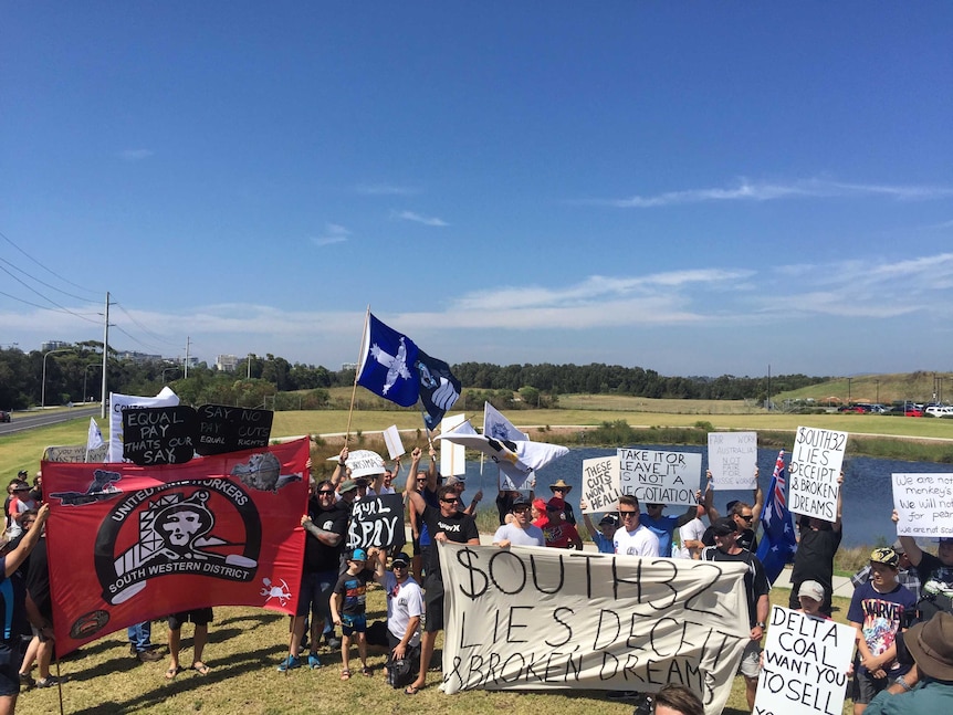 A group of protesters holding banners, flags and signs.