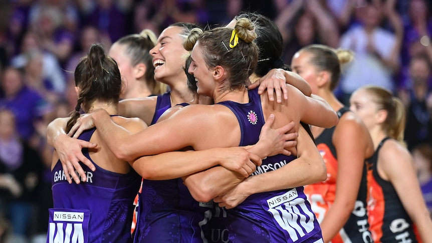 Queensland Firebirds players celebrate by hugging each other 