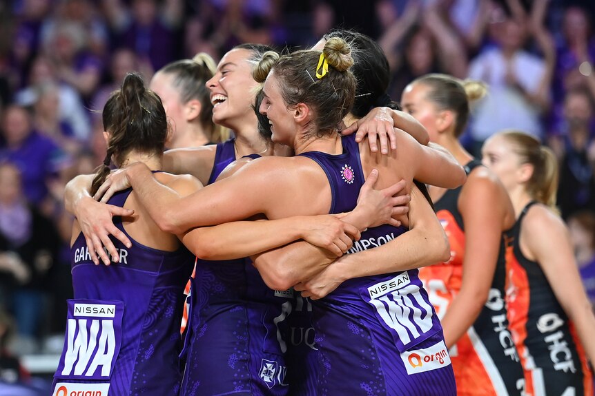 Queensland Firebirds players celebrate by hugging each other 