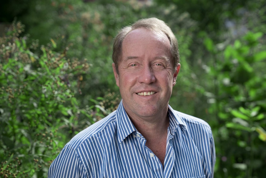 A man with brown hair smiles at the camera