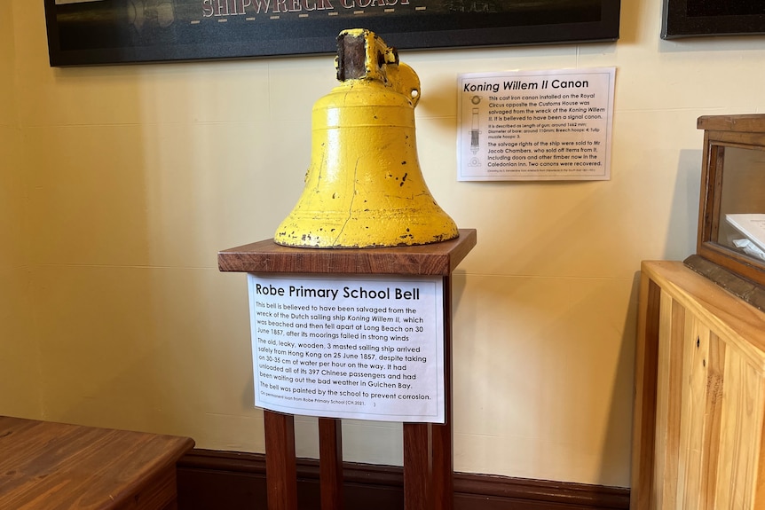 A yellow bell with placards around it