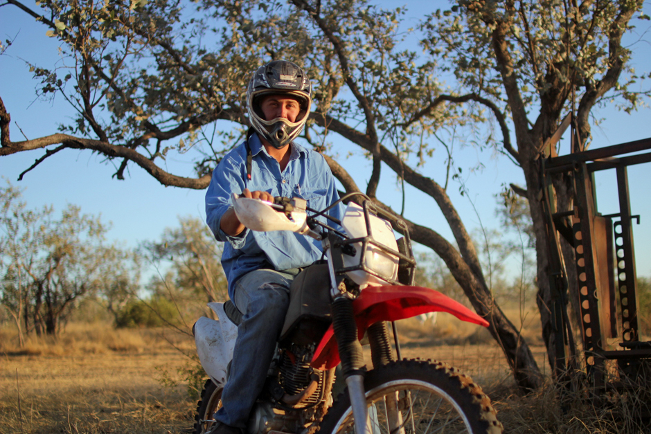A young man in a full-face helmet sits on a dirt bike.